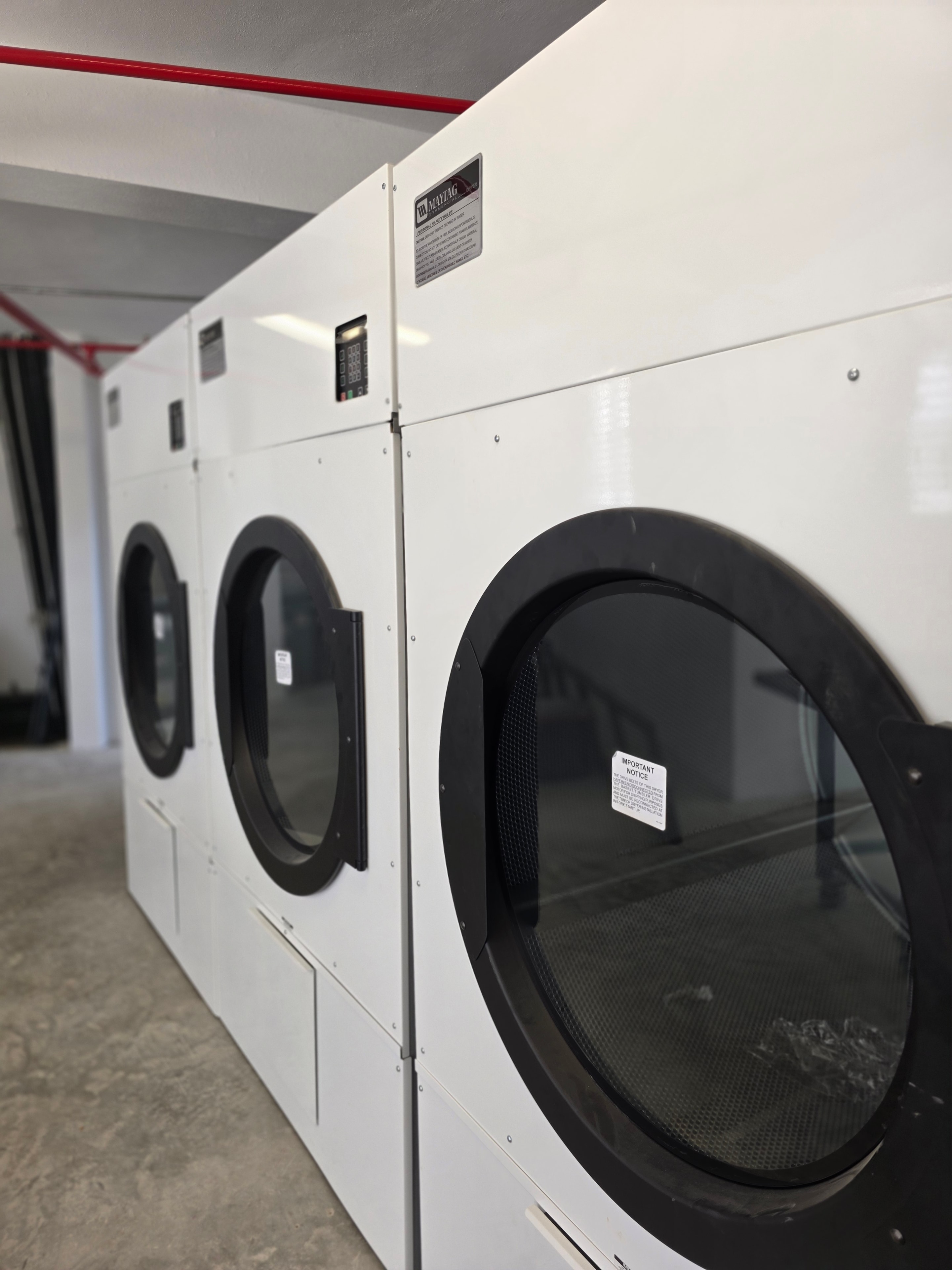 Maytag commercial dryers against dark wall